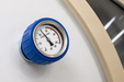 Close-up of a pressure gauge with blue casing on a white surface.