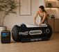 Woman zipping closed the black Elite 36 hyperbaric chamber in a luxury home wellness setting.
